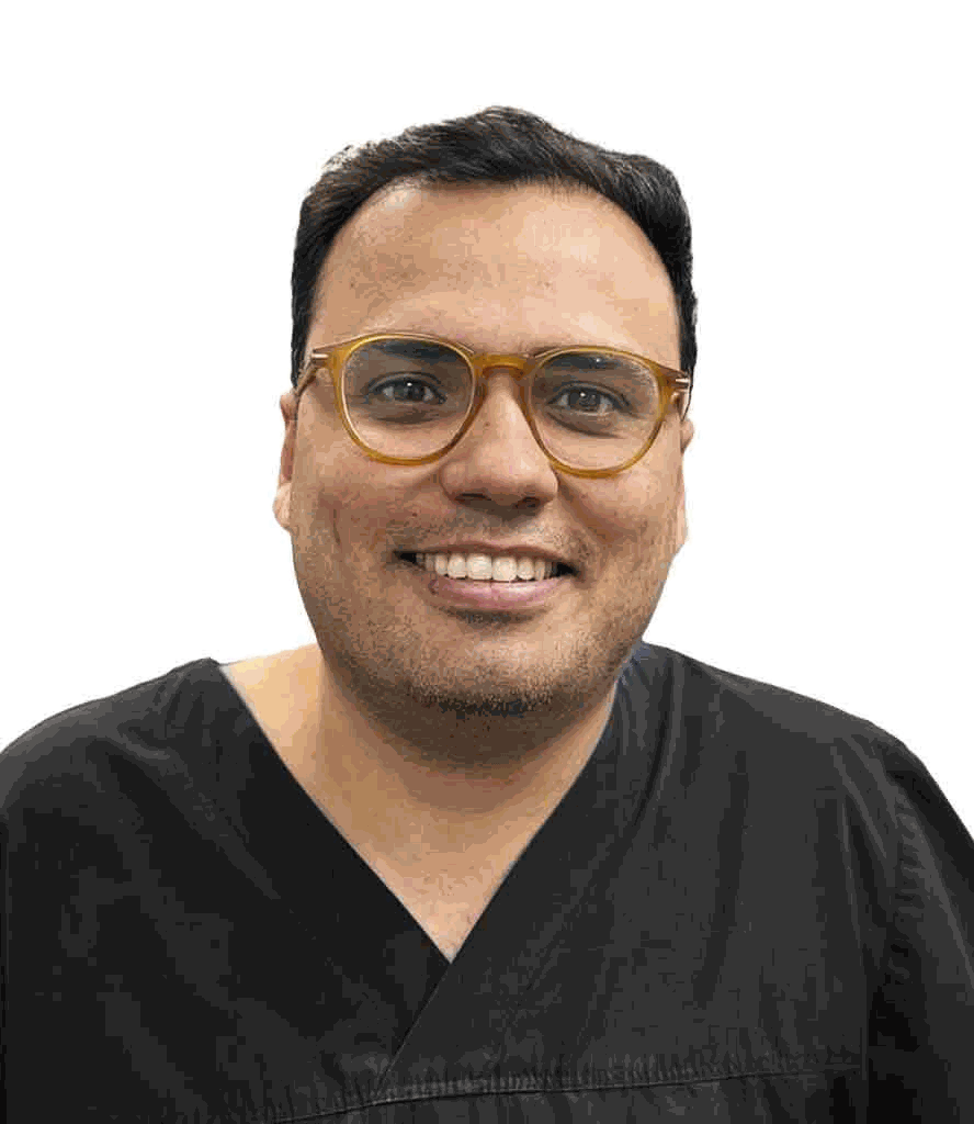 Dr Karan Singh, smiling, in black clinical scrubs